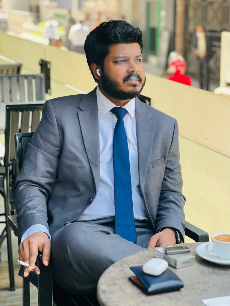 A businessman in a suit sitting at an outdoor cafe, smoking a cigarette and looking relaxed