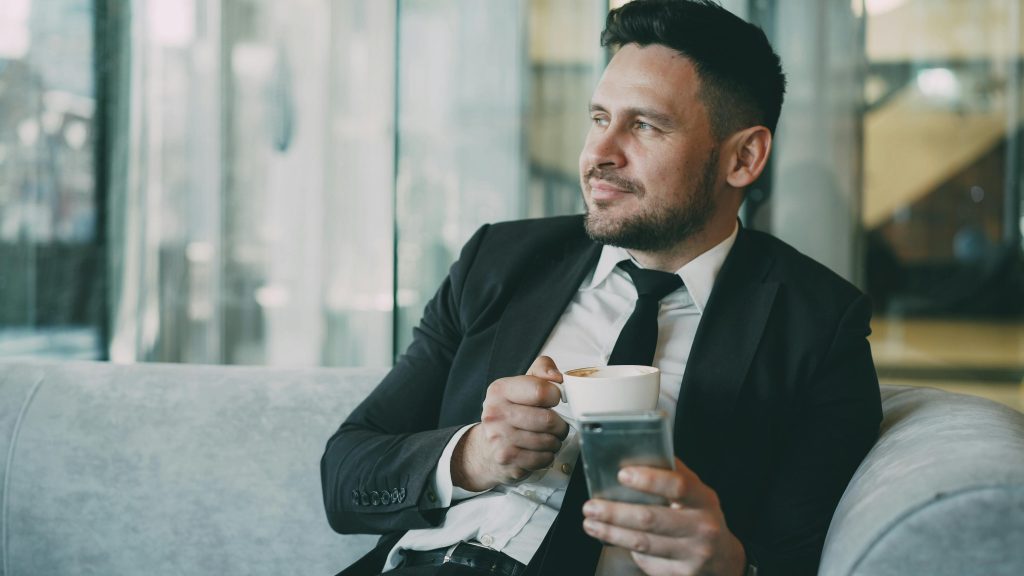 Smiling businessman enjoying coffee break in modern office